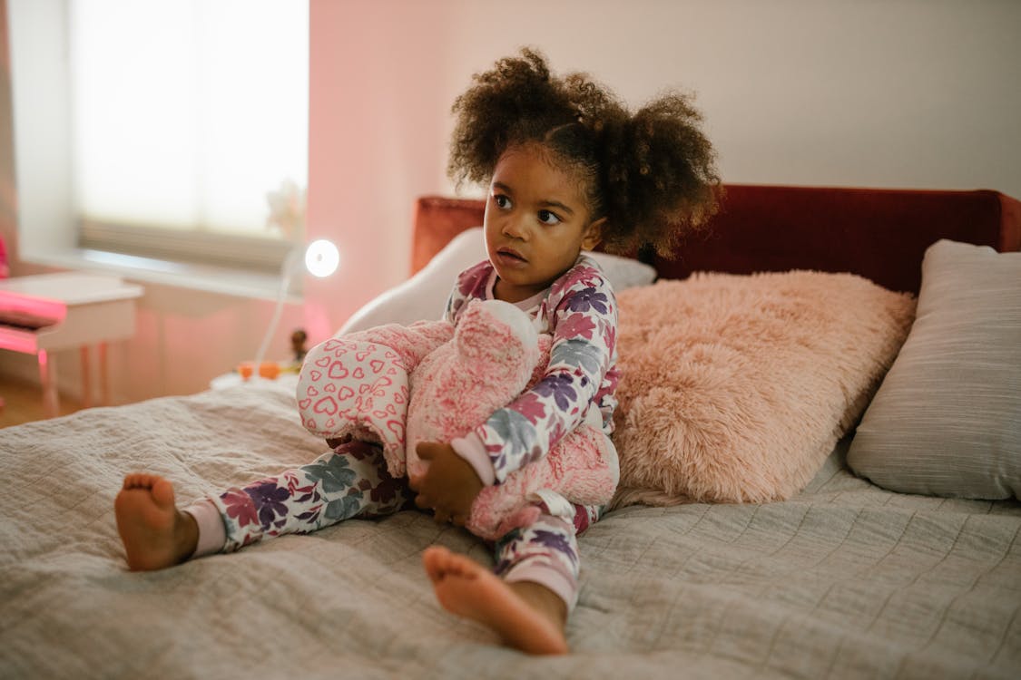 Free Child Sitting on Bed Stock Photo