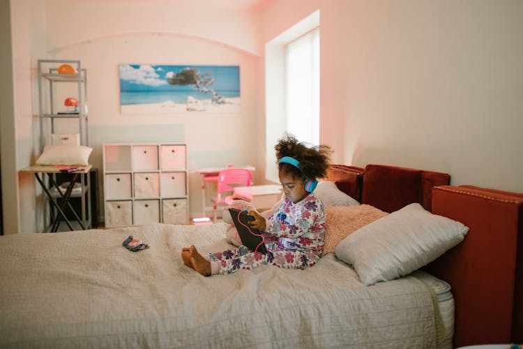 Child Listening To Music On Bed