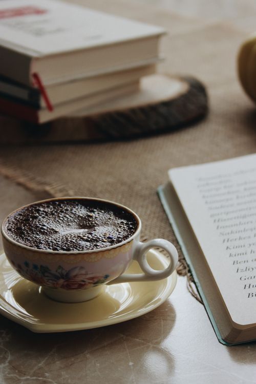 Free A warm still life with coffee cup, books, and open book on a table. Stock Photo