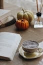 Cup of Coffee Standing Next to Open Book and Pumpkins in Background