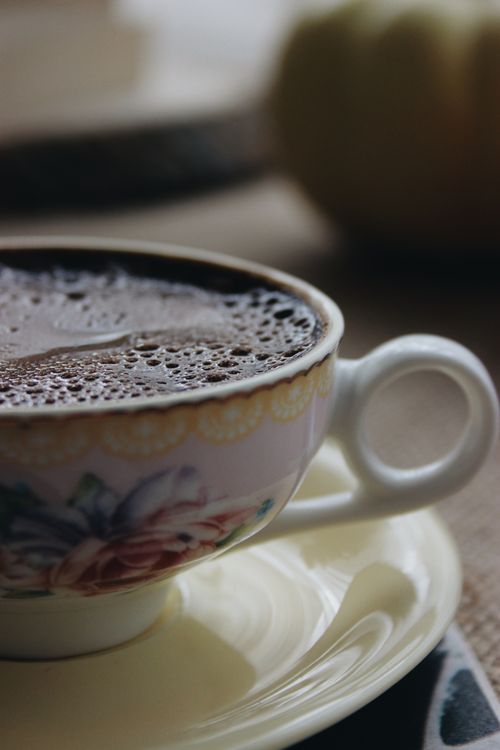Free A close-up of a steaming hot coffee in a floral ceramic cup with a blurred background. Stock Photo