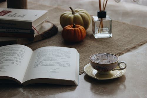 Free A Cup of Coffee on a Saucer Beside an Open Book Stock Photo