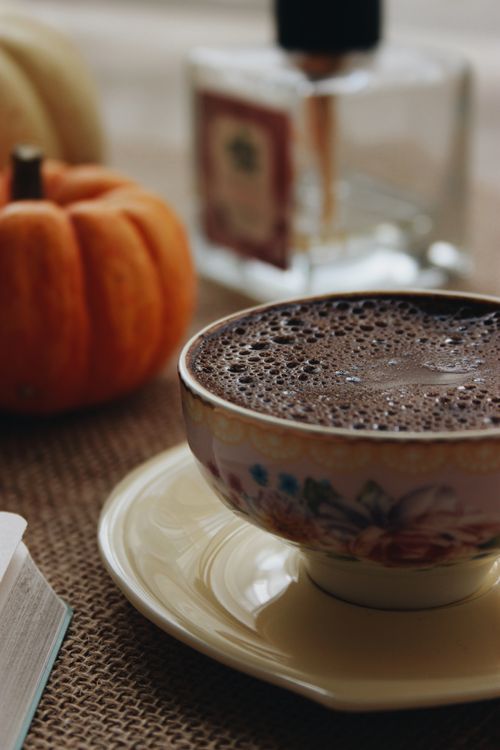 Free Warm beverage in a floral ceramic cup with pumpkin decor, perfect for autumn vibes. Stock Photo