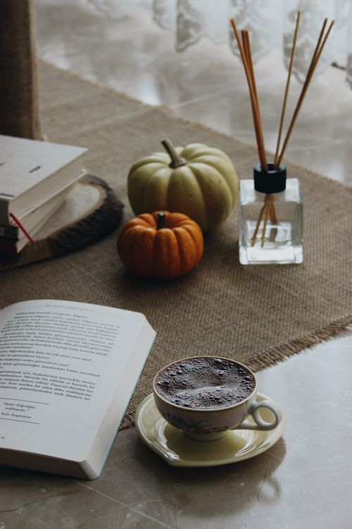 Free A warm autumn atmosphere with coffee, books, pumpkins, and diffuser sticks for a relaxing day at home. Stock Photo