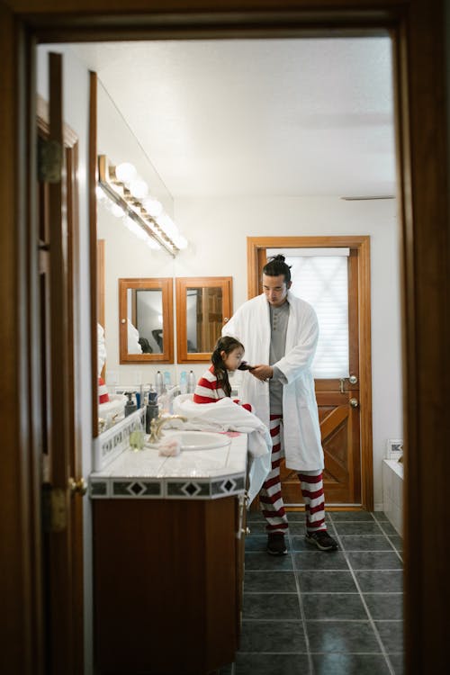 Free Father Combing Daughter Hair in Bathroom Stock Photo