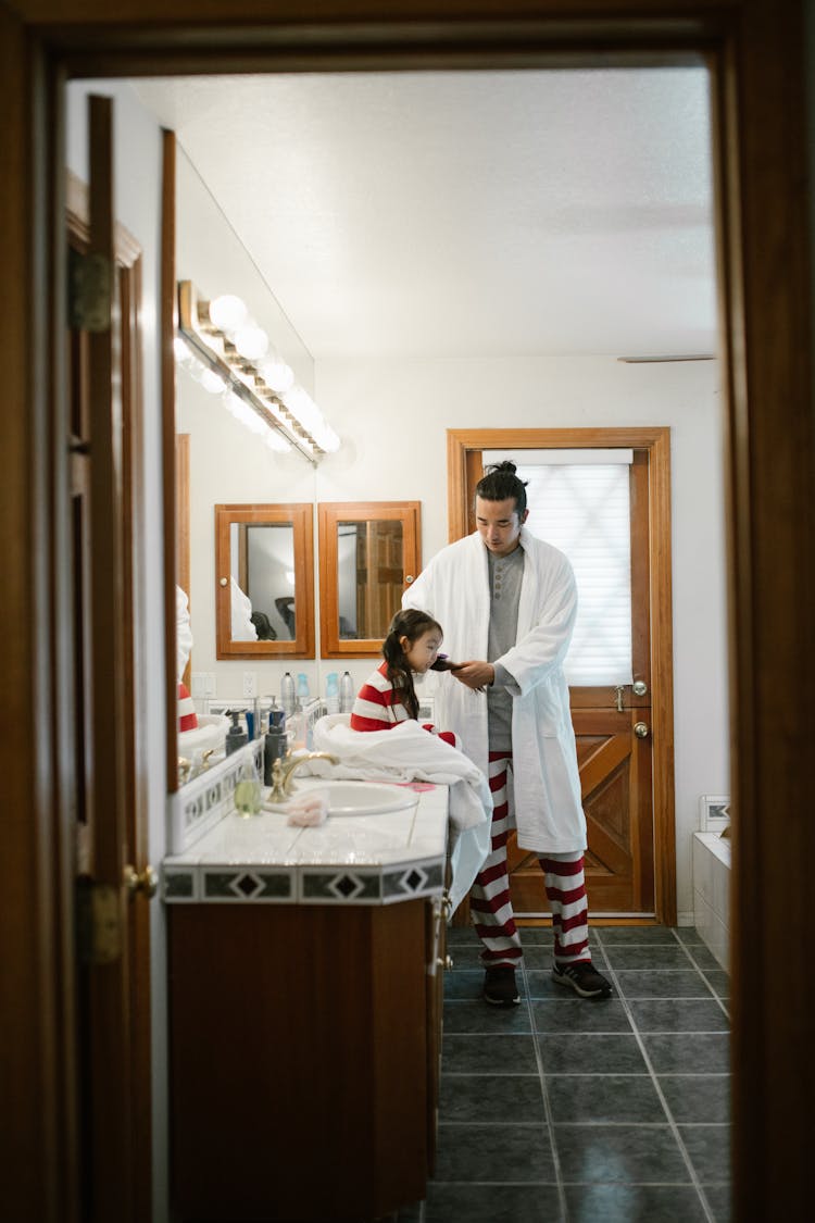 Father Combing Daughter Hair In Bathroom