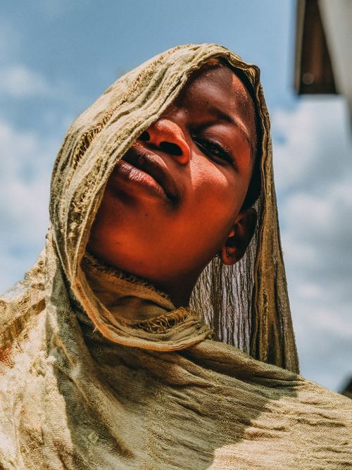 Free Close-up portrait of a young African woman wearing a headscarf against a blue sky. Stock Photo
