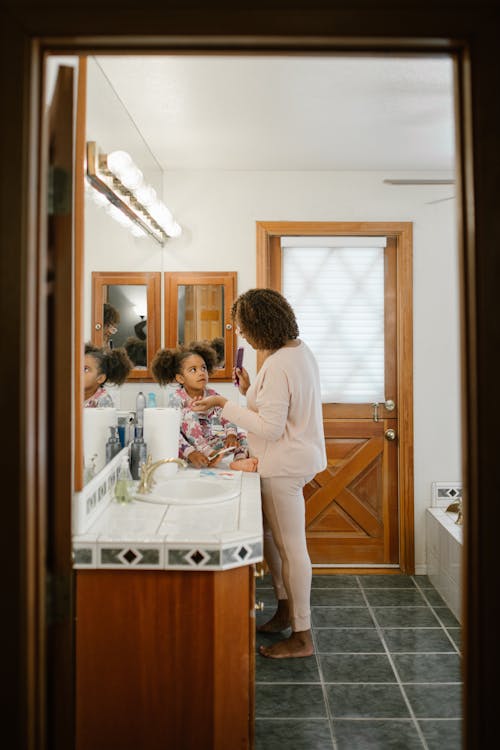 Free Mother Combing Daughter Hair in Bathroom Stock Photo