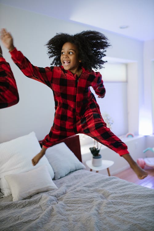 Curly Haired Girl Jumping on Bed
