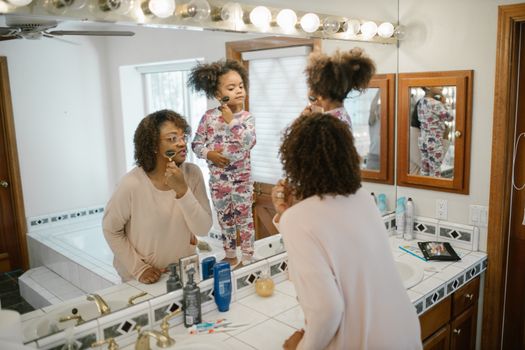 A mother and daughter enjoy a morning skincare ritual together in the bathroom.