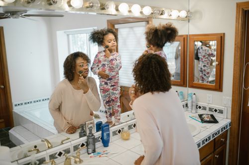 Free A mother and daughter enjoy a morning skincare ritual together in the bathroom. Stock Photo