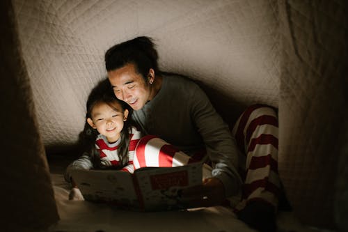 Free Father and Daughter Reading Book under Blanket Stock Photo