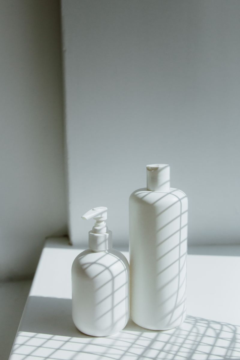 Two unlabelled white bottles on a sunlit shelf with window shadows