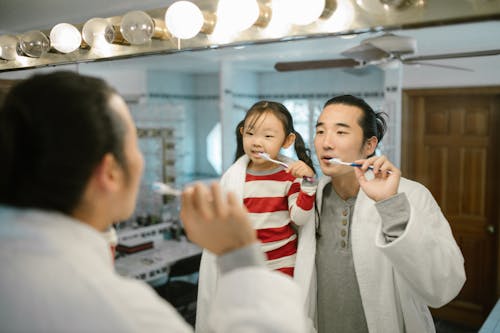 Free Daughter Brushing Teeth with Father Stock Photo