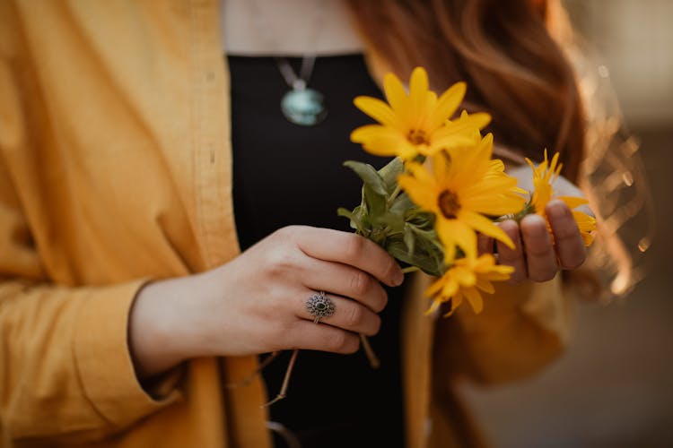 Female Hands Holding Small Bunch Of Orange Flowers