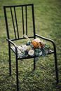 Bunch of Flowers Laying on Black Metallic Chair Standing on Lawn