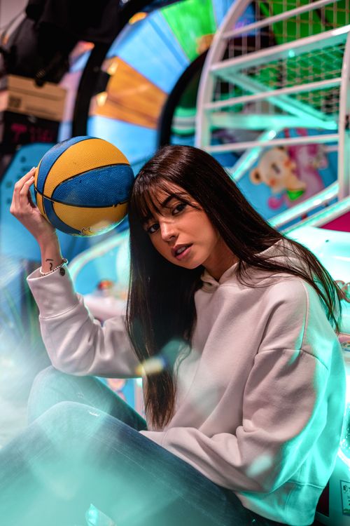 Free Stylish woman in arcade holding basketball, vibrant and colorful scene. Stock Photo