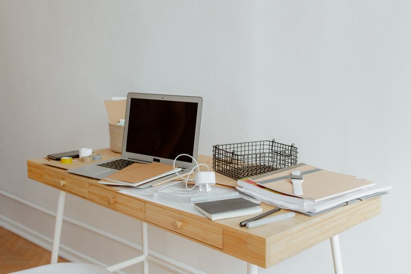 Desk with laptop and loose white charging cables scattered across it — the typical small-apartment cord mess before organizing