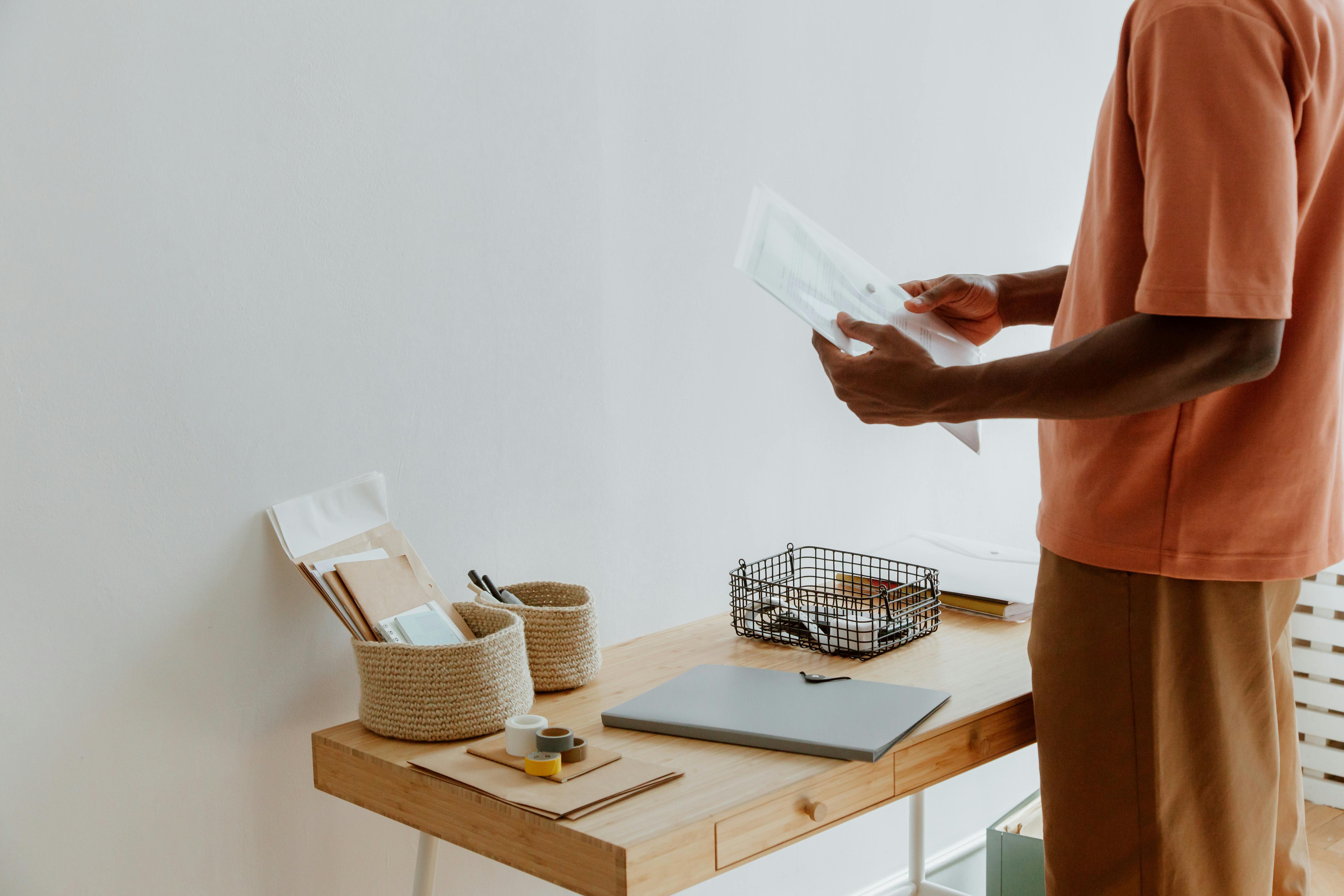 A man in a casual outfit organizes papers on a modern office desk.