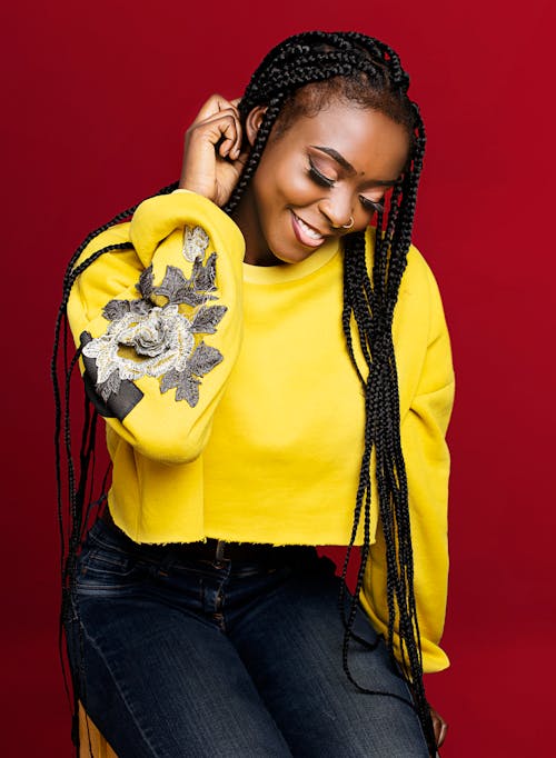 A Smiling Woman in Yellow Sweater Sitting while Looking Down