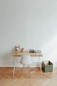Clean and simple home office setup featuring a wooden desk, chair, and storage box in a minimalist style.
