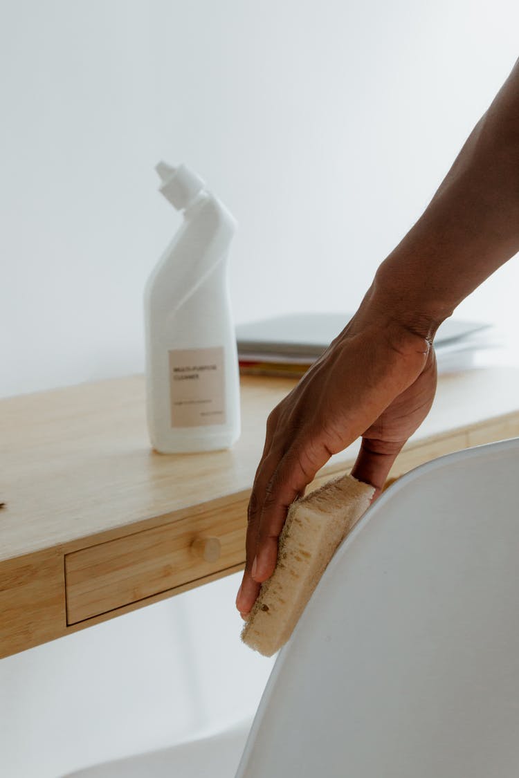 Man Cleaning Desk Area With Sponge 