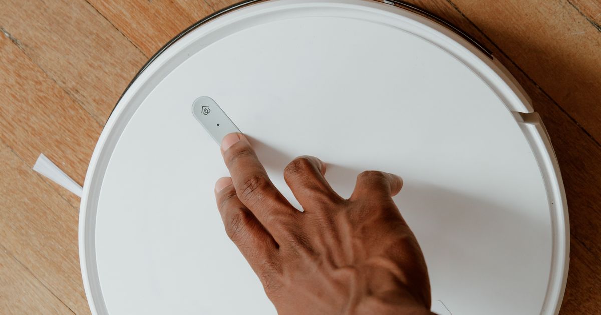 Hand startet einen Reinigungsroboter per Knopfdruck
