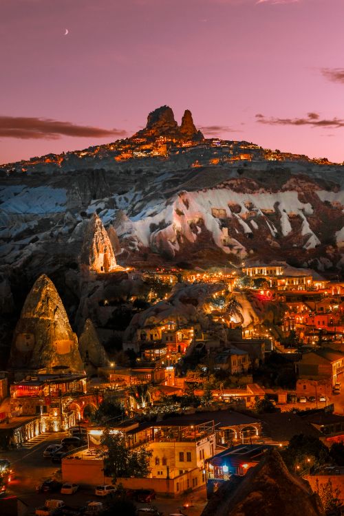 Free A breathtaking aerial view of Cappadocia at sunset, featuring illuminated landscapes and a pink sky. Stock Photo