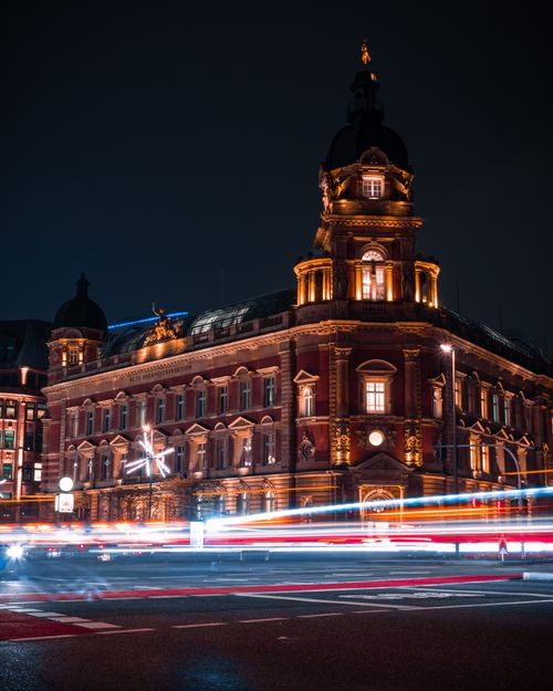 Free Night view of a historic landmark in Hamburg with vibrant light trails illuminating the streets. Stock Photo