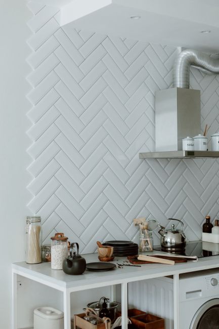 Stylish kitchen with modern appliances, utensils, and a herringbone backsplash.