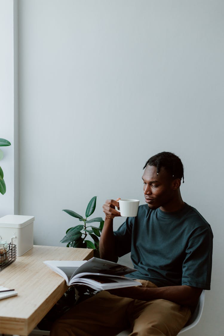 Man Drinking Coffee While Reading Magazine