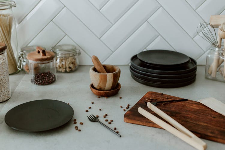 Jars, Plates, Mortar, Cutting Board And Coffee Beans On Kitchen Counter