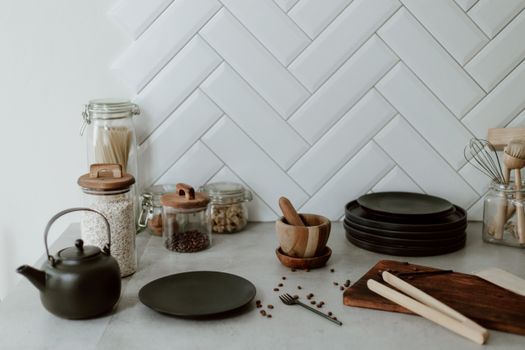 A minimalist kitchen setup with jars, plates, and a kettle on a modern countertop.