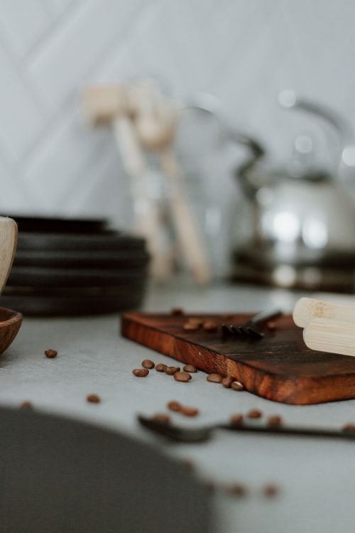 Free A cozy kitchen scene with coffee beans on a wooden cutting board and plates, creating a warm homely ambiance. Stock Photo