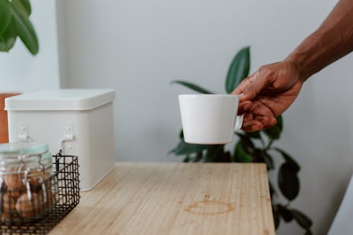Free Hand Holding Cup and Boxes on Table Stock Photo