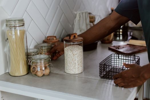 Modern kitchen counter with glass jars of pasta and walnuts, showcasing organization.