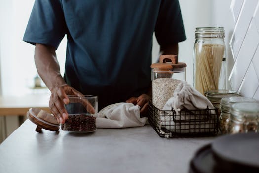 A man organizing a kitchen counter with glass jars filled with food items and cloth covers.