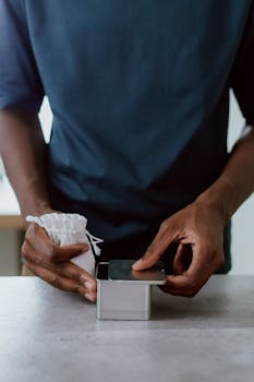 Close-up of a man opening a metal box containing coffee beans, with a cloth bag beside.