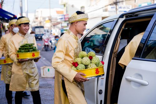 Free Men in traditional attire carrying fruit offerings for a Vietnamese wedding. Stock Photo