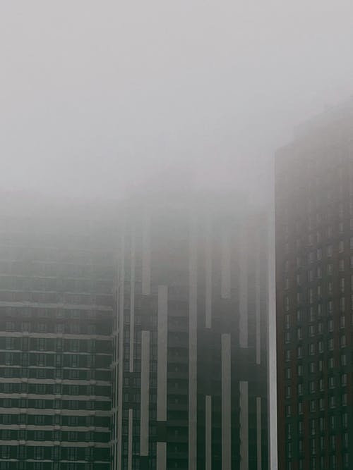 Free A Grayscale Photo of a City Buildings with Fog Stock Photo