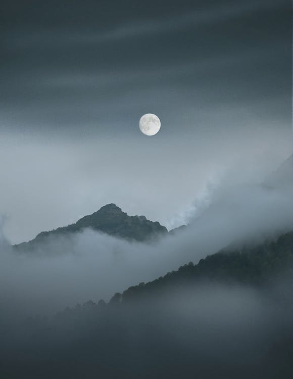 Full Moon over Foggy Mountains Covered With Clouds