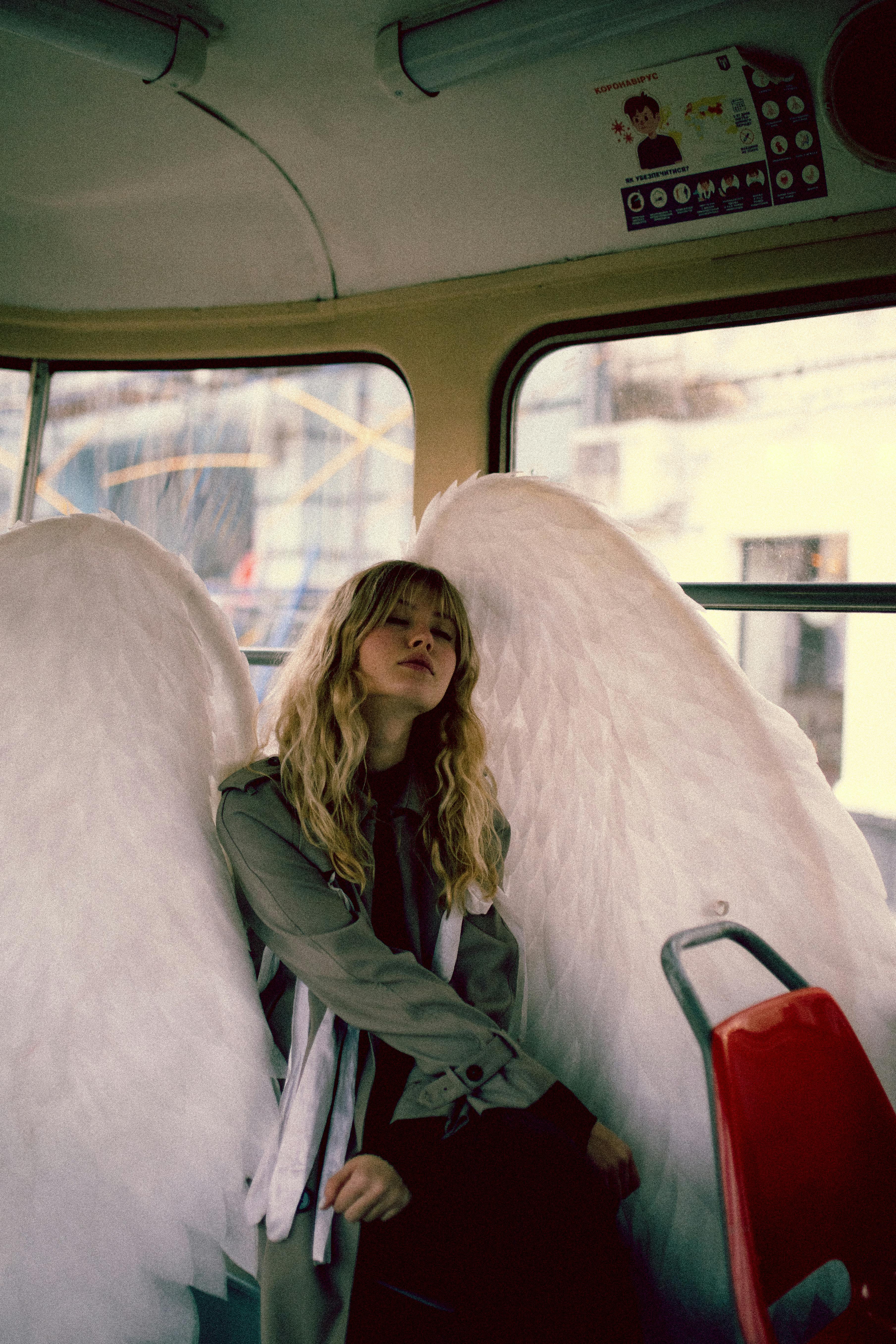 blond woman with long hair sitting on city bus and posing as angel