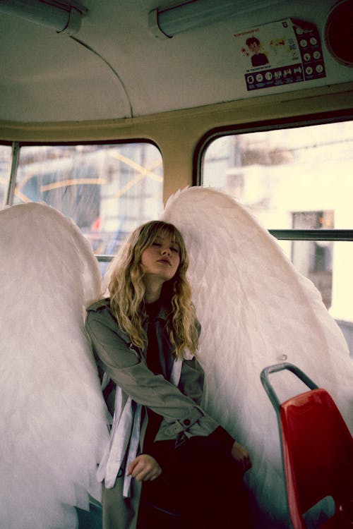 Free Blond Woman with Long Hair Sitting on City Bus and Posing as Angel Stock Photo