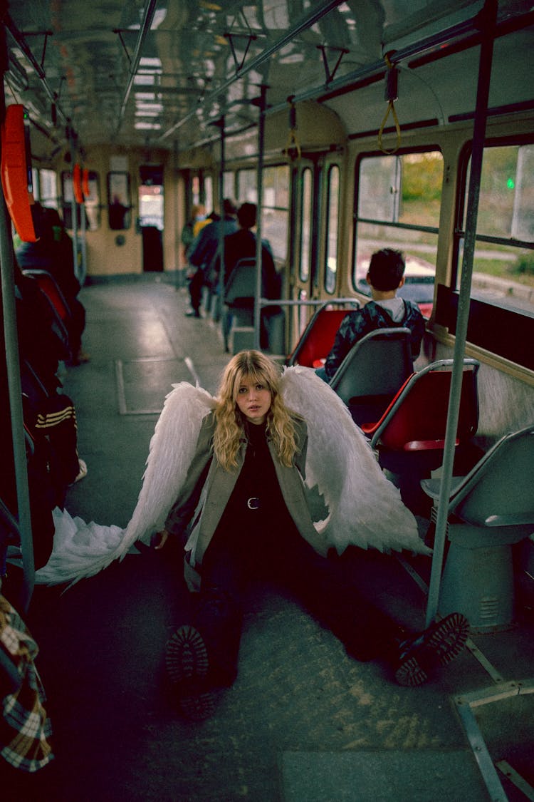 Young Blond Woman On Bus Posing As Angel With White Wings