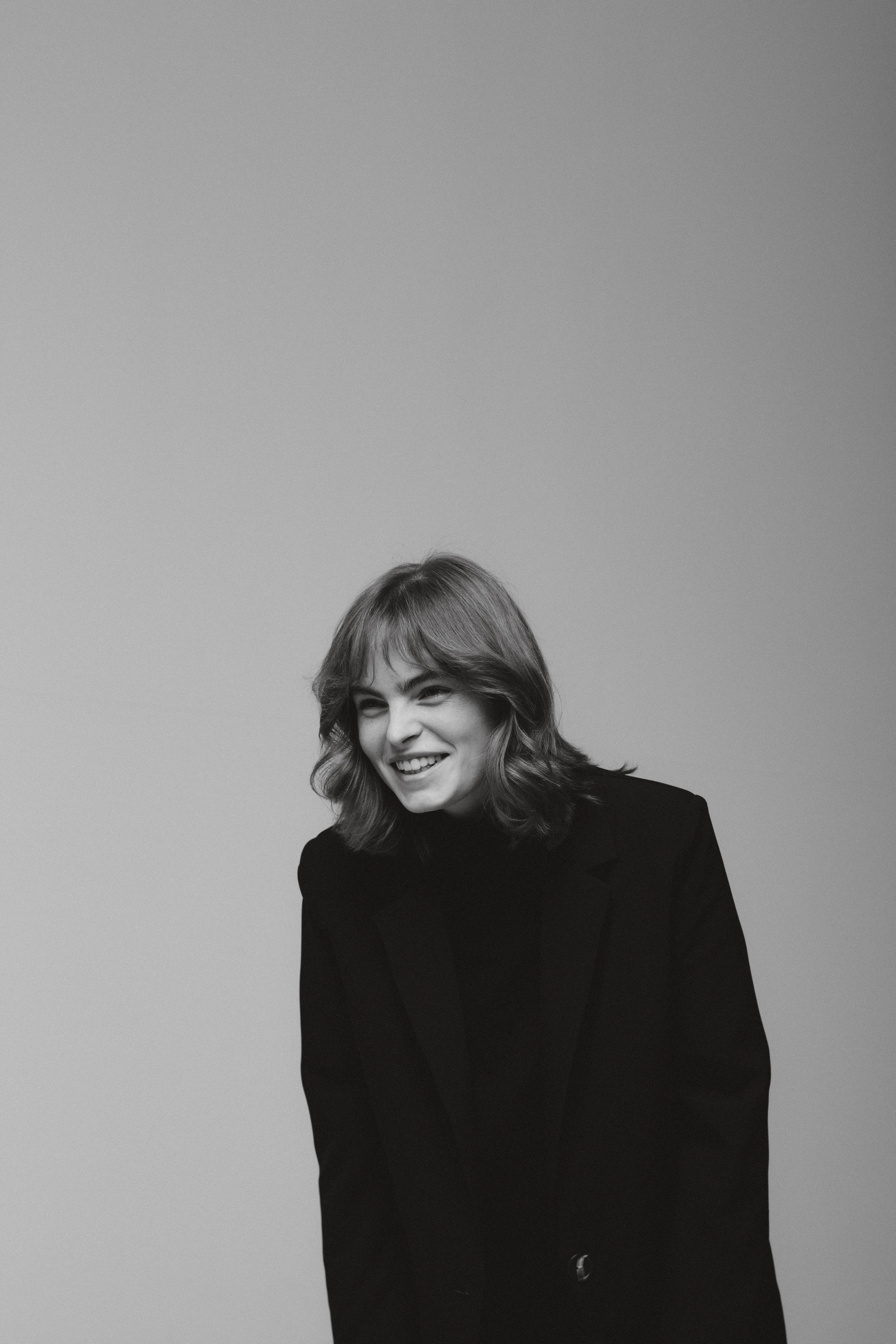 Elegant black and white portrait of a smiling woman in a studio setting.