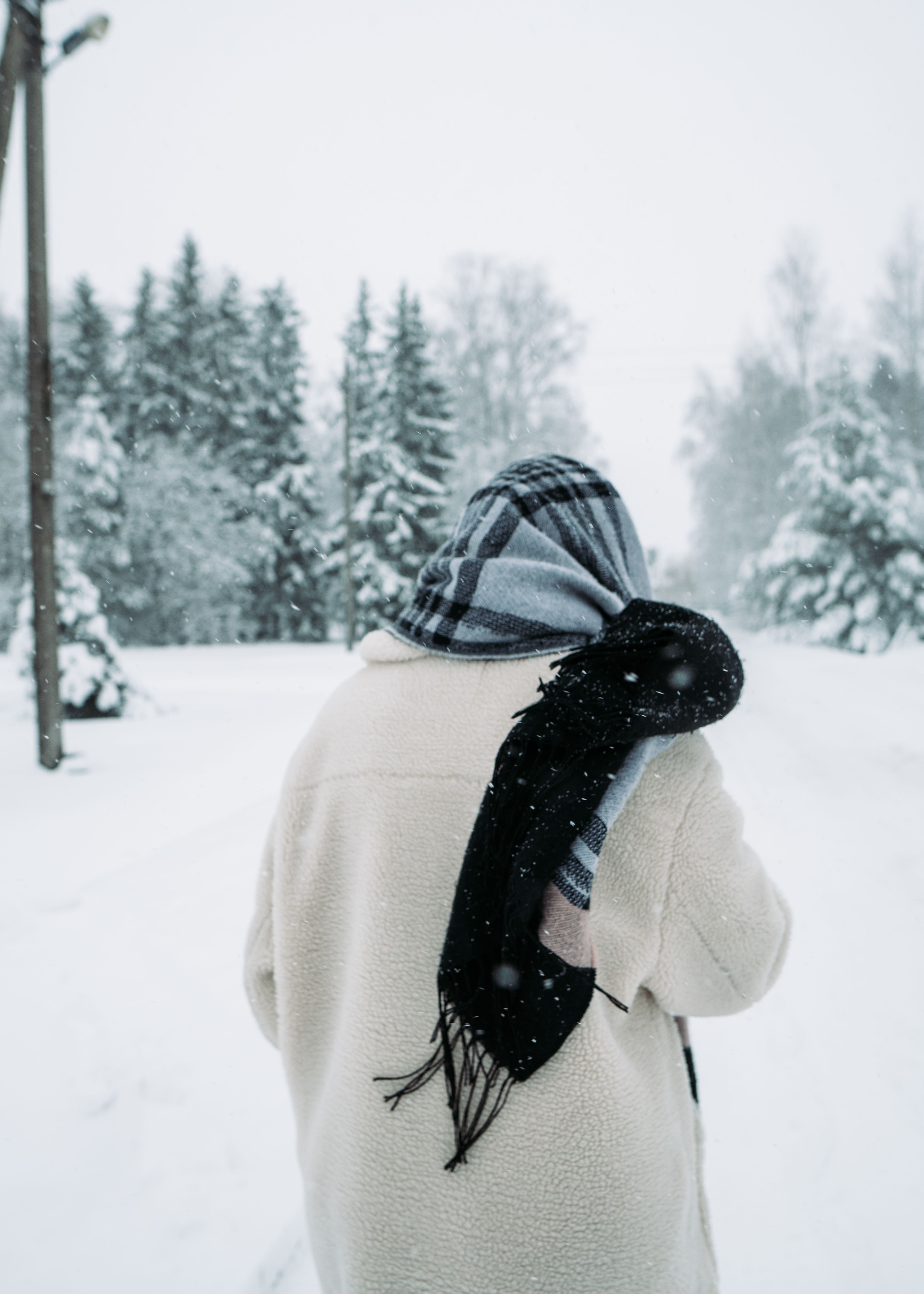 Unrecognizable person in winter clothes walking through snow-covered forest in Lithuania.