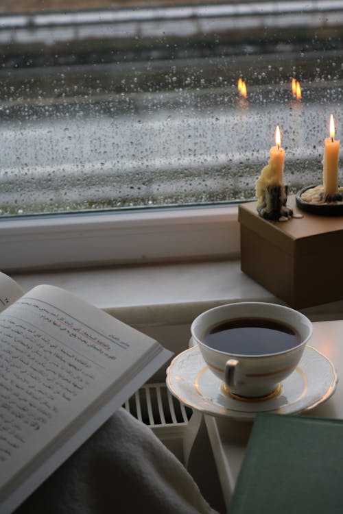 Free A Cup of Coffee Near the Glass Window with Lighted Candles Stock Photo