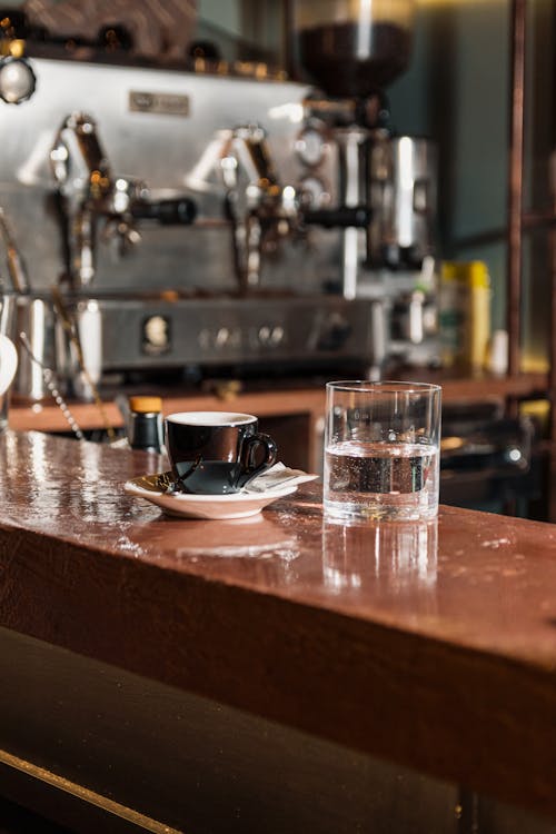 A Cup of Coffee Beside a Glass of Water on a Counter Top