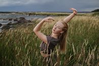 A Woman in Gray Shirt Standing on Grass Field