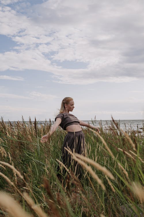 Woman Standing in Tall Grass by the Sea